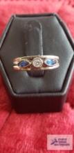 Silver colored ring with one clear gemstone and two blue gemstones, marked 925